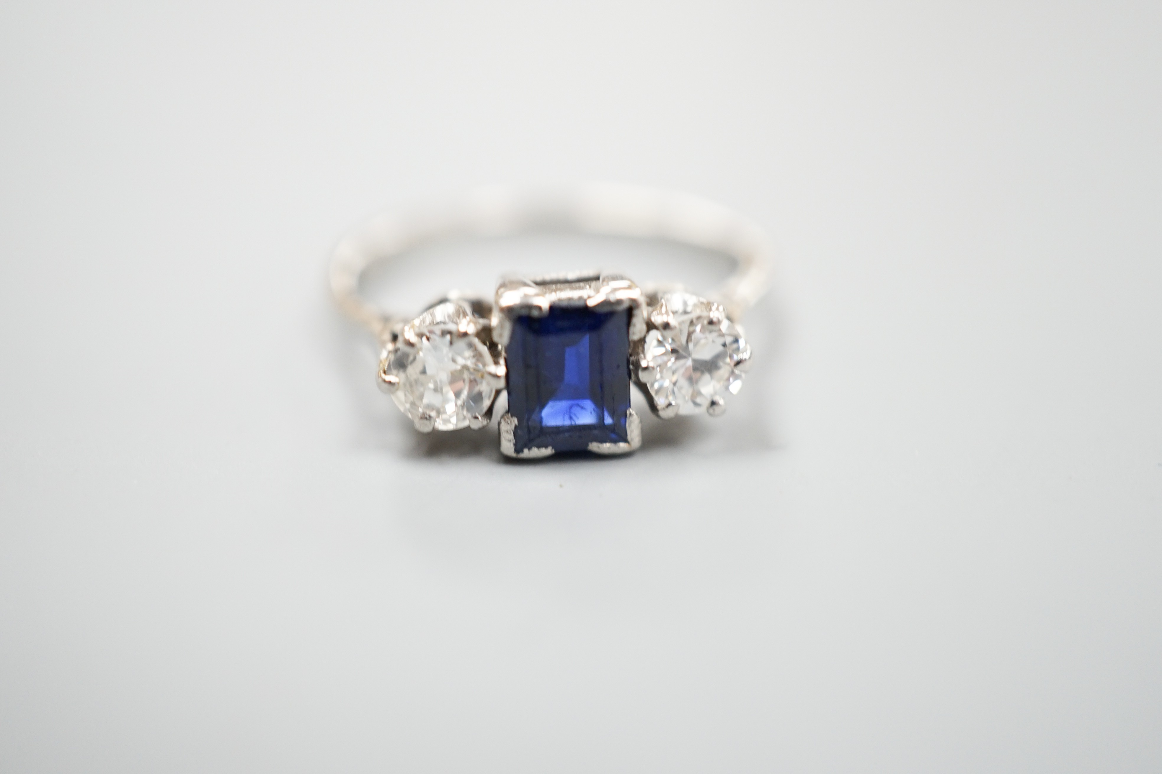 A white metal (stamped plat), sapphire and diamond set three stone ring, size K, gross weight 3.6 grams.